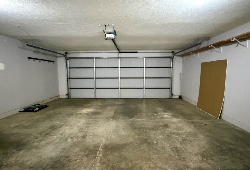 Spacious garage with a sectional overhead door, automatic opener, and concrete flooring