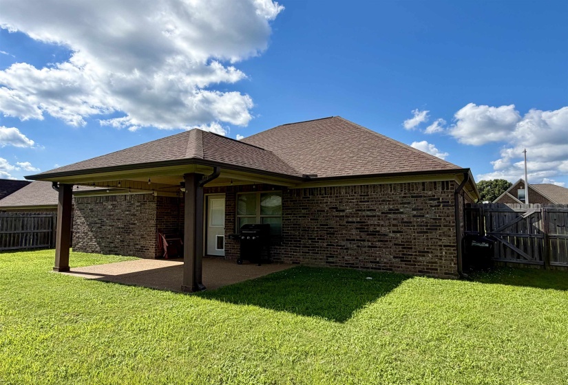 Brick exterior featuring a covered patio, exposed aggregate patio surface, and a wooden privacy fence