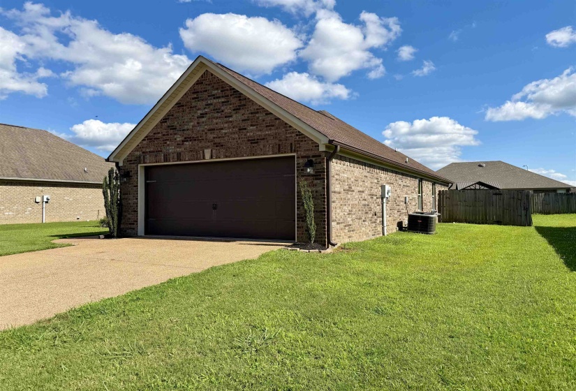 Brick exterior with a brown garage door, featuring a concrete driveway and grassy side yard