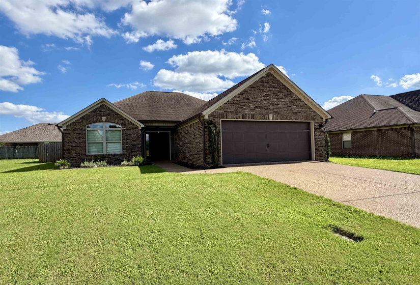 Brick exterior with a prominent arched window, a two-car garage, and a concrete driveway