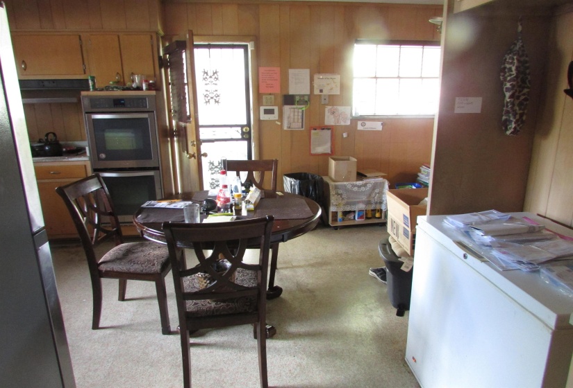 Kitchen area with wood paneling, wood-finish cabinetry, and double wall ovens