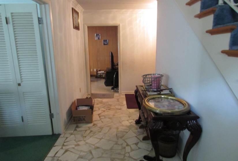 Foyer featuring irregular tile flooring, white walls, and a staircase with carpeted treads