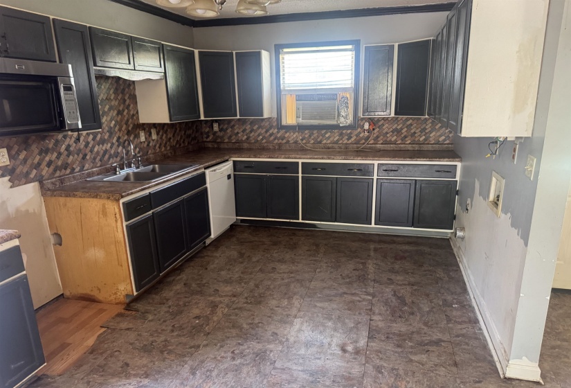 Kitchen featuring extensive cabinetry with dark wood-finish doors and light trim, a stainless steel double basin sink, and a built-in microwave
