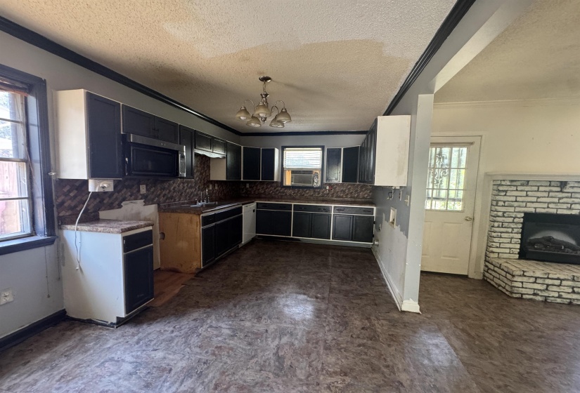 Expansive kitchen with dark cabinetry, patterned backsplash, and an integrated microwave
