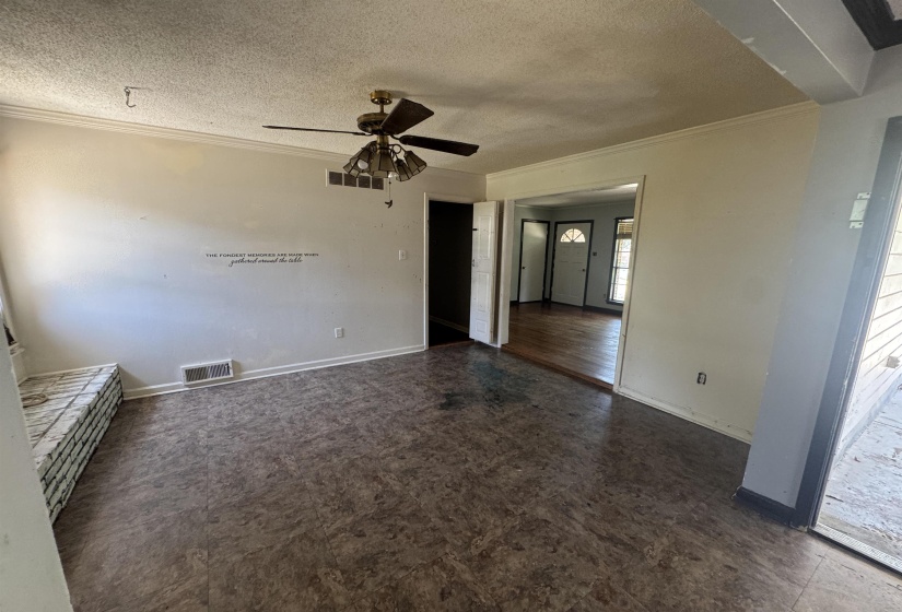 Spacious room featuring textured flooring, crown molding, and a ceiling fan with integrated lighting