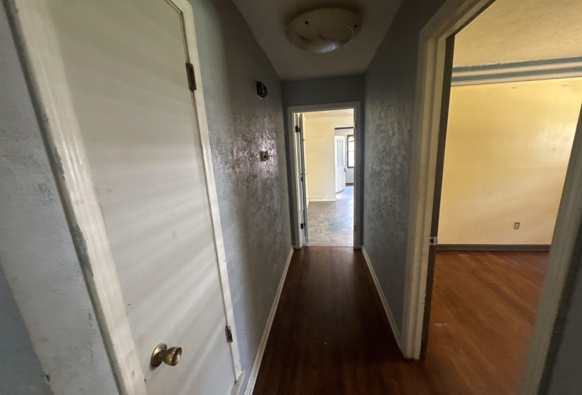 Hallway featuring wood-finish flooring, light blue walls, and a flush-mount ceiling light