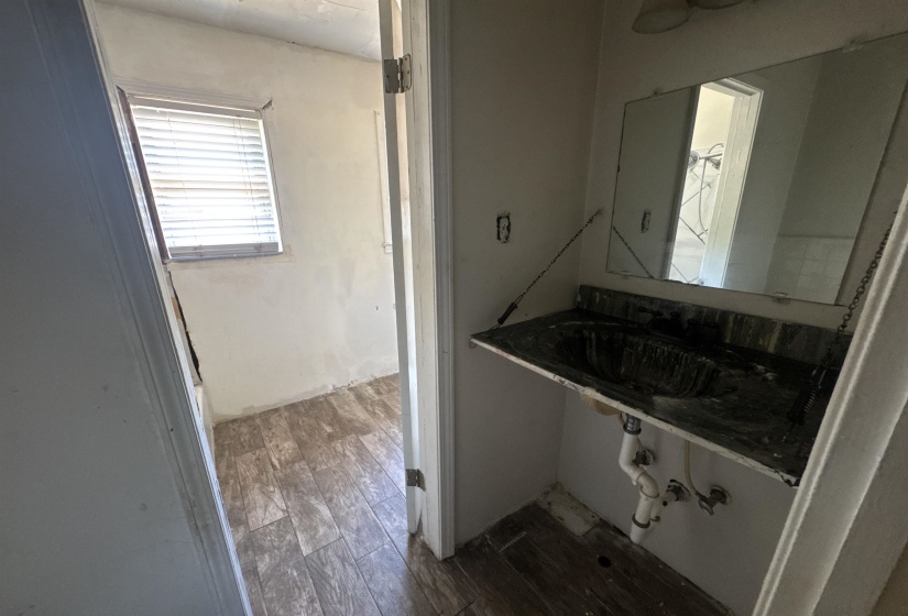 Bathroom featuring a wall-mounted vanity with integrated sink, overhead lighting fixture, and a window with horizontal blinds