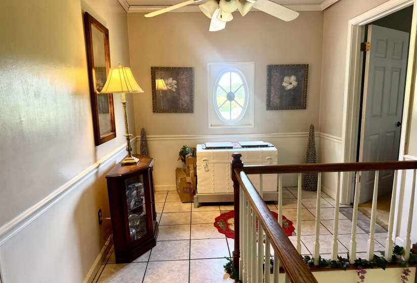 Tiled entryway featuring wainscoting, an oval window, and a ceiling fan