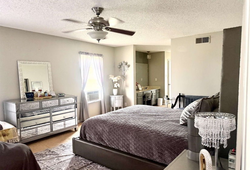 Light-toned interior space with wood-finish flooring, a ceiling fan with integrated lighting, and a window with a window-mounted unit