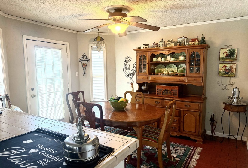Dining area featuring a ceiling fan with integrated lighting, a white paneled door with louvered blinds, and a window with louvered blinds