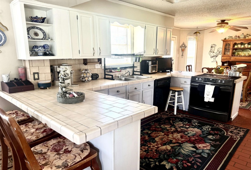 Kitchen with white cabinetry, tile countertops, and a tile backsplash