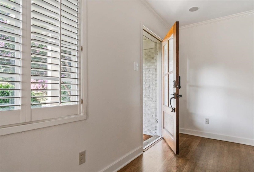 Wood-finish flooring with white baseboards and crown molding