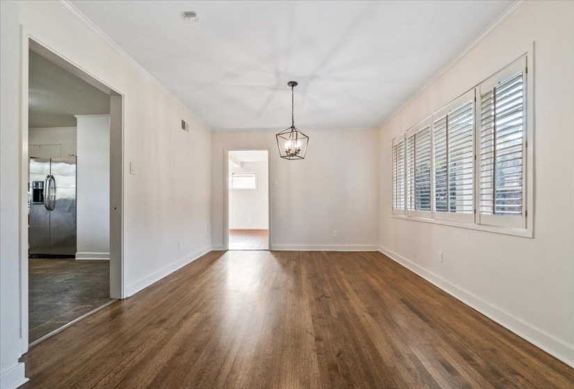 Spacious room featuring wood-finish flooring, white walls, and a contemporary black metal chandelier