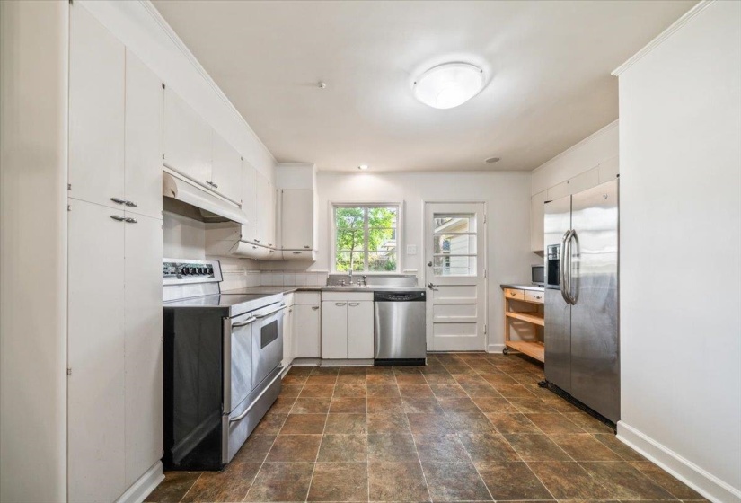 Kitchen featuring white cabinetry, stainless steel appliances, tile flooring, and a window above the sink