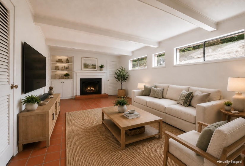Living area featuring a fireplace with white mantel, integrated shelving with accent lighting, and terra cotta-style flooring