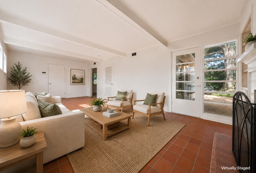 Spacious living area featuring terra cotta tile flooring, exposed ceiling beams, white walls, and a glass-paneled exterior door