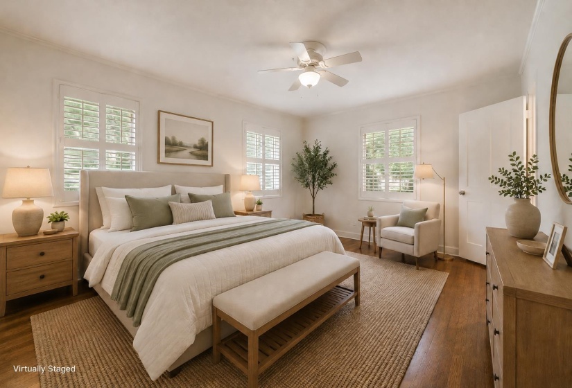 Bright bedroom featuring hardwood flooring, white plantation shutters, a ceiling fan with integrated lighting, and a white paneled door