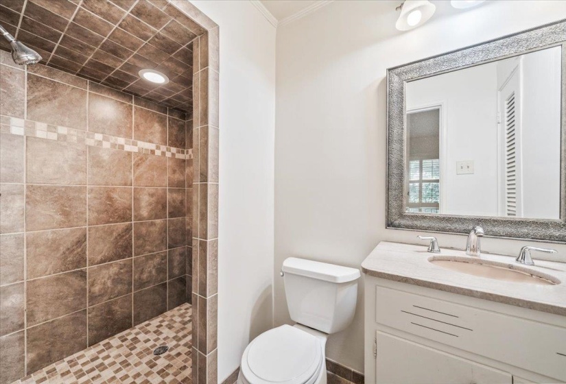 Tiled walk-in shower with a decorative accent band and recessed lighting