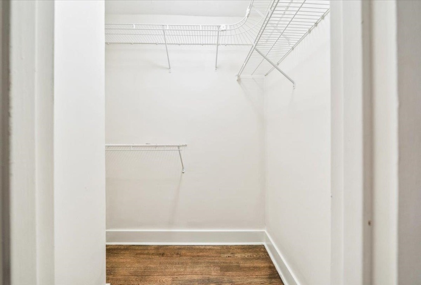 Walk-in closet featuring wood-finish flooring, white walls, white baseboards, and white wire shelving
