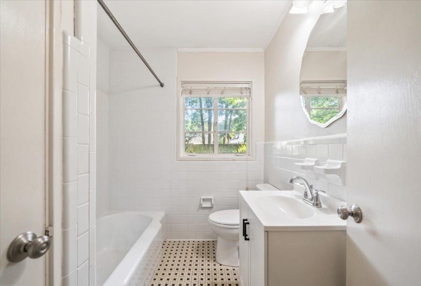 Bathroom featuring white subway tile surround, a white bathtub, and a window with blinds
