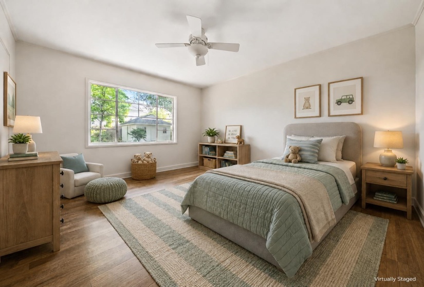 Bright bedroom featuring wood-finish flooring, a contemporary ceiling fan, and a large window with white trim