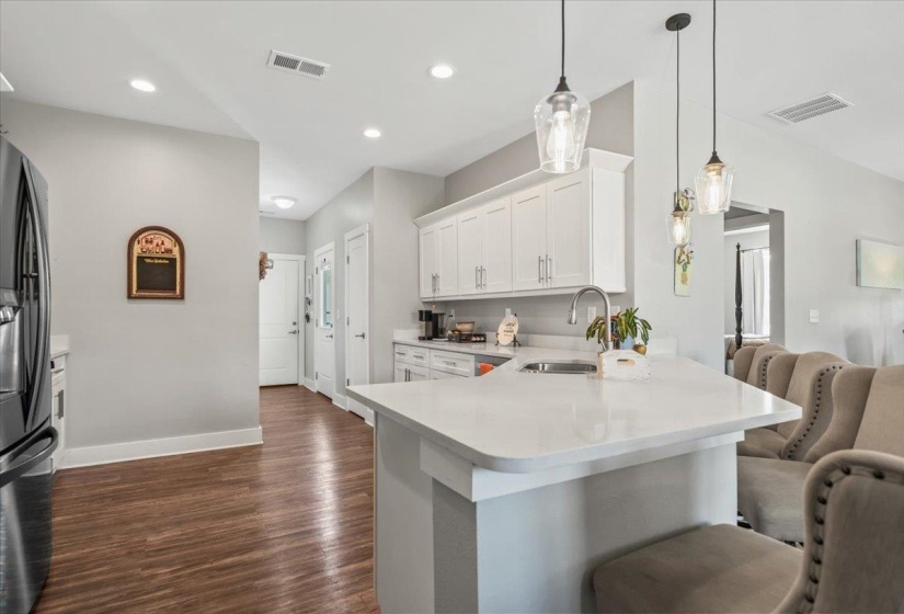 Kitchen featuring a stainless steel sink, white cabinetry, integrated range hood, and pendant lighting