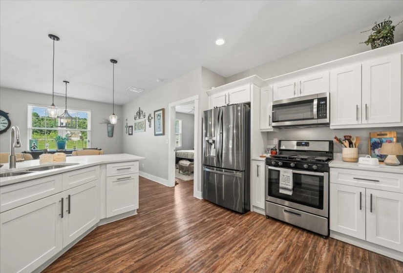 Modern kitchen featuring white cabinetry, stainless steel appliances, and wood-finish flooring
