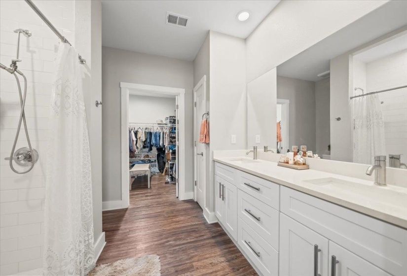 Bathroom featuring a dual vanity with white cabinetry, light-colored countertops, and brushed nickel fixtures
