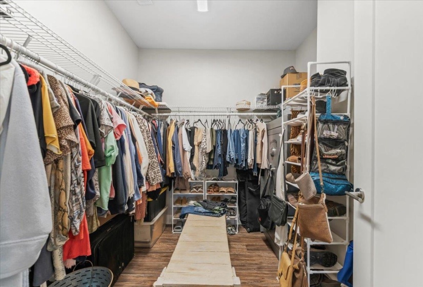 Spacious walk-in closet featuring wood-finish flooring, white walls, and extensive wire shelving with hanging rods