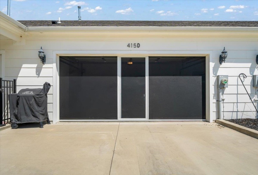 Attached garage with white siding, equipped with a three-panel sliding screen door system