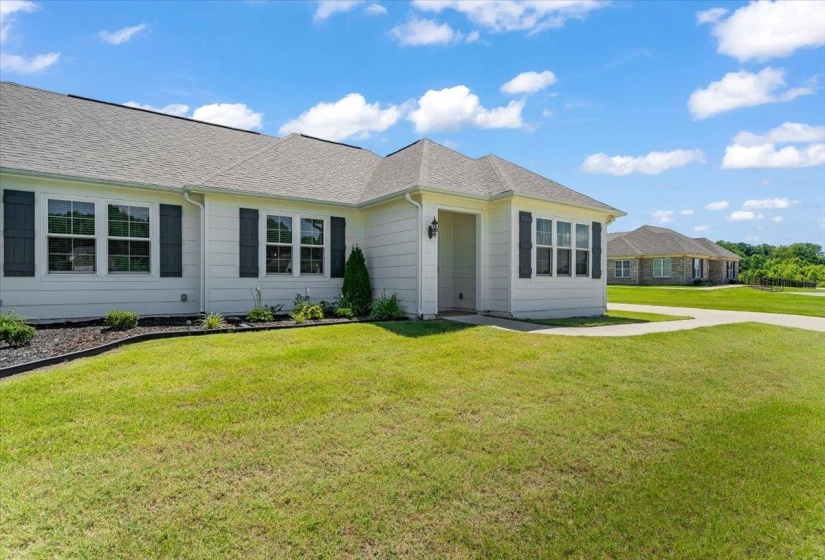 Single-story home featuring a light-colored exterior siding, dark louvered shutters, and a gray shingle roof