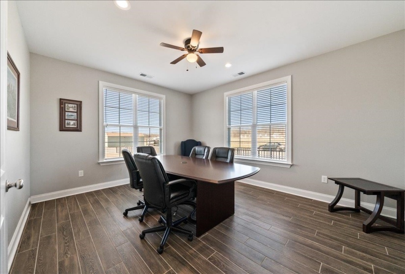 Room featuring wood-finish flooring, two large windows with blinds, recessed lighting, and a ceiling fan with integrated light