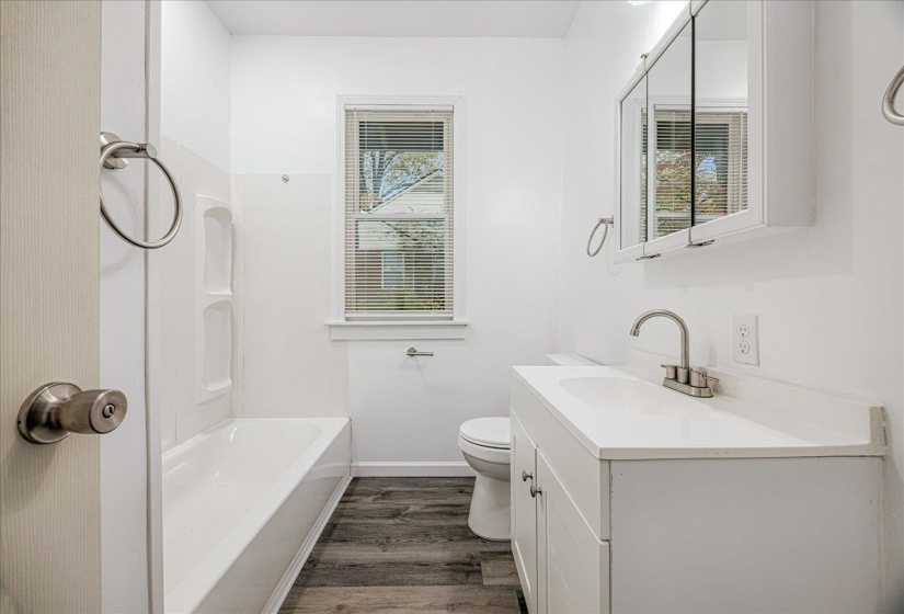 Full bath with vanity, dark wood-style floors, and washtub / shower combination