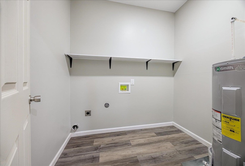 Laundry area featuring water heater, hookup for a washing machine, light wood-style floors, and electric dryer hookup