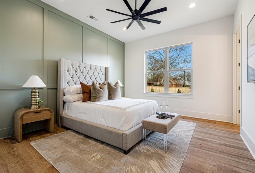 Bedroom with light wood-type flooring, ceiling fan, recessed lighting, and a decorative wall