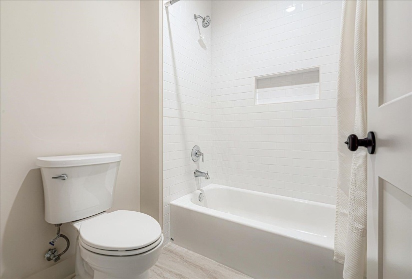 Bathroom featuring toilet and shower / tub combo with curtain