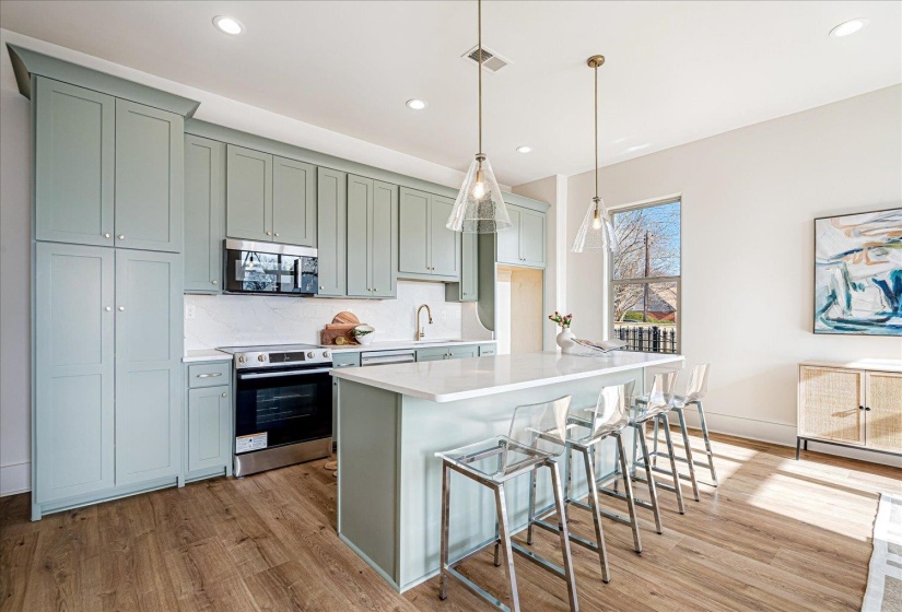Kitchen featuring stainless steel appliances, a center island, pendant lighting, a kitchen bar, and light wood-style floors
