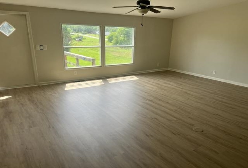 Spacious room featuring wood-finish flooring, neutral wall tones, and a ceiling fan