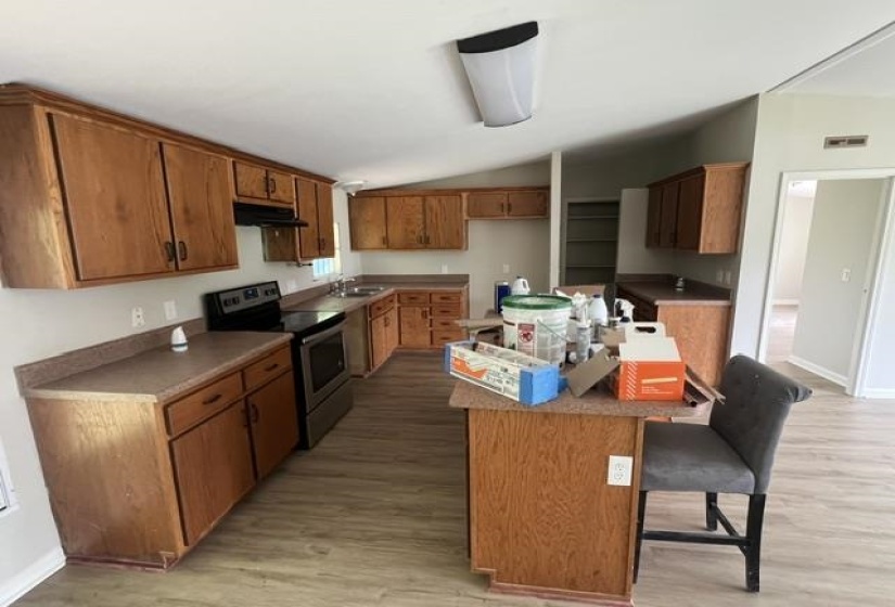 Spacious kitchen featuring extensive wood cabinetry, laminate countertops, a stainless steel range, and wood-finish flooring