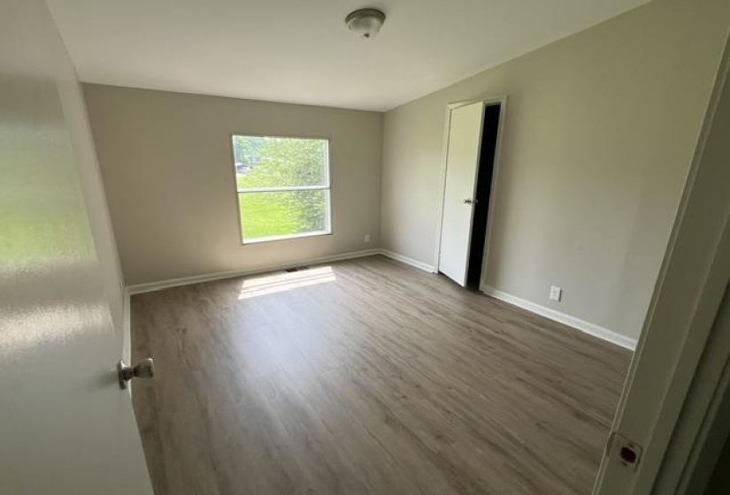Interior space featuring wood-finish flooring, light-toned wall paint, a window, and a ceiling-mounted light fixture