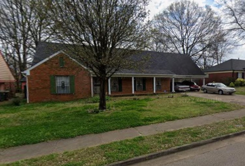 Brick ranch-style home featuring a covered front porch with white columns, green window shutters, and a dark shingle roof