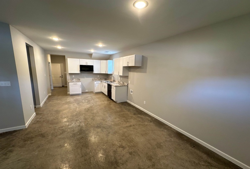 Kitchen featuring white cabinetry, concrete floors, and black appliances