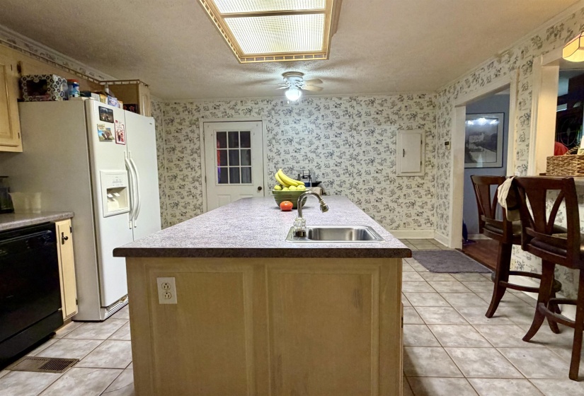 Kitchen featuring an island with an integrated sink and light-toned countertop, complemented by tiled flooring