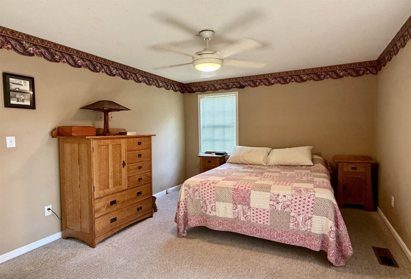 Carpeted room featuring neutral wall paint, a ceiling fan with integrated lighting, a window with blinds, and decorative border trim
