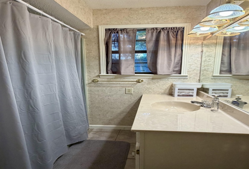 Bathroom featuring a single vanity with an integrated sink, polished chrome faucet, and a large wall mirror