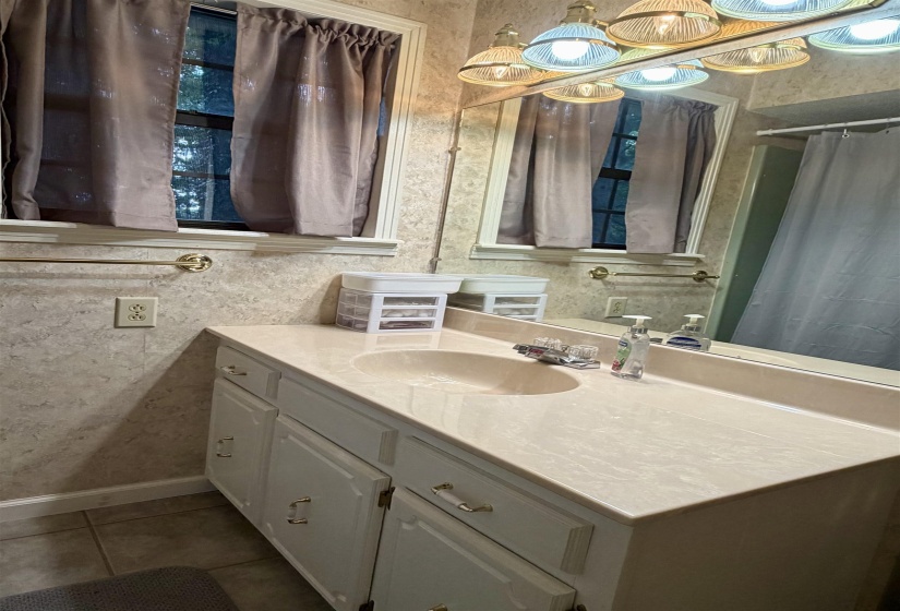 Bathroom vanity featuring an integrated sink, light-toned countertop, and white cabinetry with decorative pulls