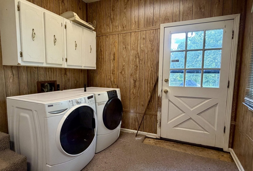 Laundry area featuring wood-finish wall paneling and overhead white cabinetry