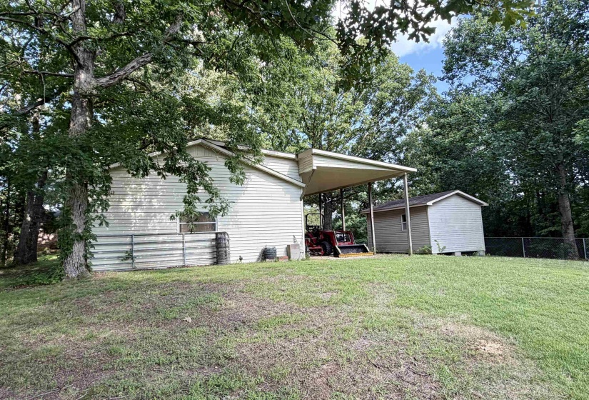 Exterior featuring tan siding, a covered carport, and a detached storage shed