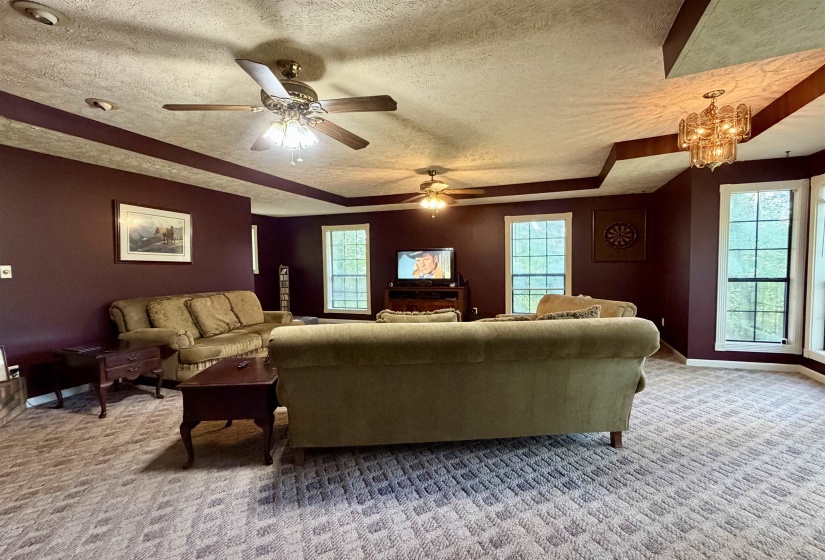 Spacious living area featuring textured ceilings, multiple windows, recessed lighting, and ceiling fans