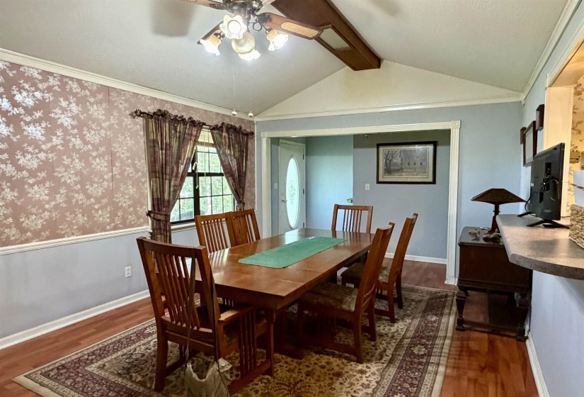 Room featuring a vaulted ceiling with a ceiling fan, wood-finish flooring, and a window with trim
